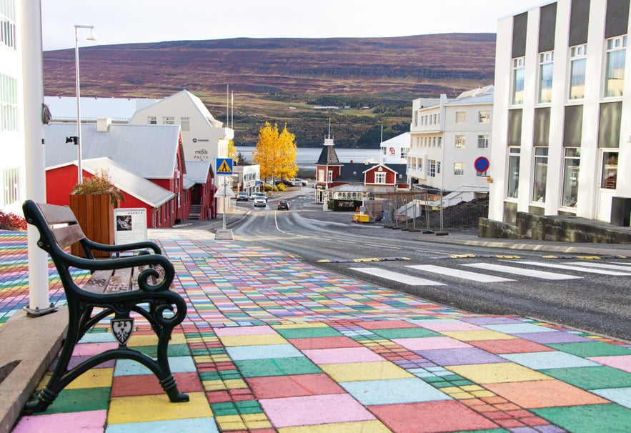 Colorful tiled street with a bench overlooking downtown Akureyri, Iceland, with fjord and mountains in the background